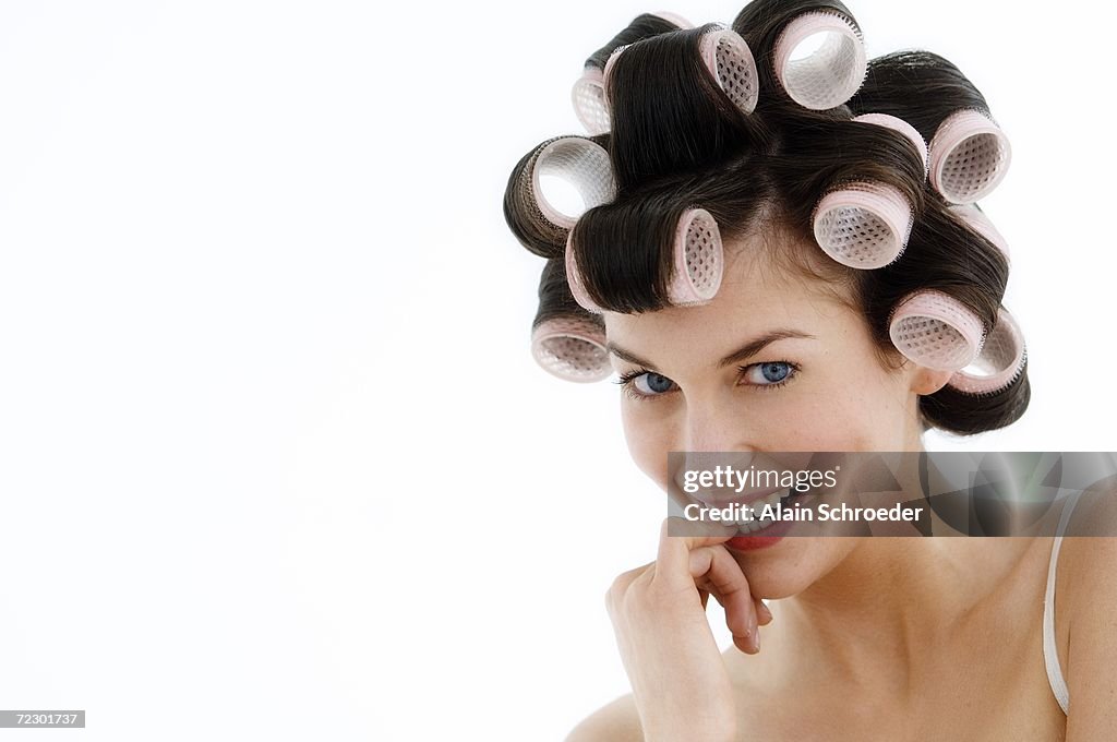 Portrait of a young woman in curlers, close up (studio)