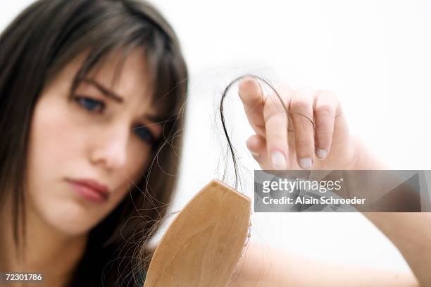 portrait of a young woman brushing her hair, close up (studio) - human hair stockfoto's en -beelden