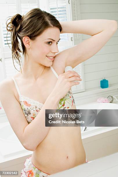 young woman in underwear using deodorant in front of bathroom mirror - deo frau badezimmer stock-fotos und bilder