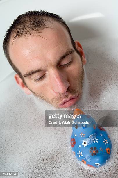 man having a bath, playing with a plastic duck - bath duck stock pictures, royalty-free photos & images