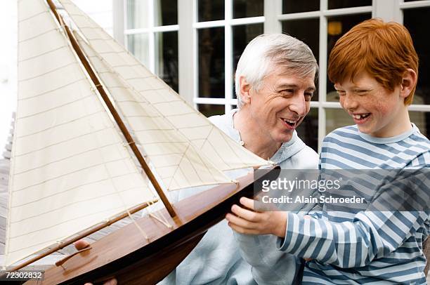 senior man and boy holding a model boat, outdoors - age contrast stock pictures, royalty-free photos & images