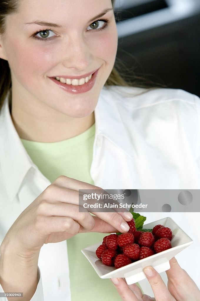 Portrait of a young woman eating raspberries