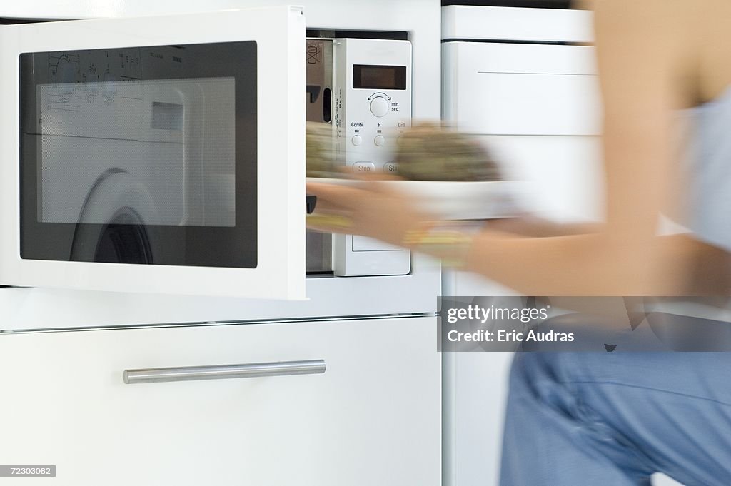 Woman using a microwave, close-up