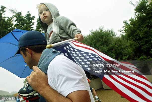 Two year old Zachary Shaw of Alexandria, Virginia holds an American flag on his father Marc's shoulders as they watch the Memorial Day Paradeon...