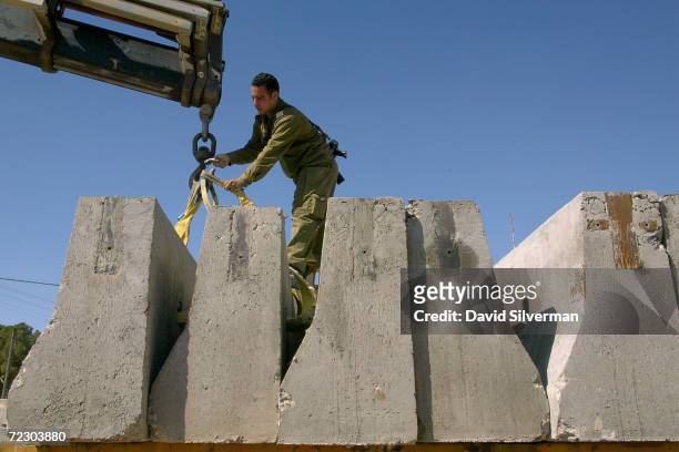 An Israeli soldier delivers concrete barriers to reinforce an army roadblock February 20, 2002 in the West Bank town of Ramallah. Israeli Prime...