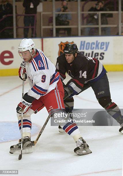 Pavel Bure works against Scott Lachance of the Vancouver Canucks while making his debut as a member of the New York Rangers at Madison Square Garden...