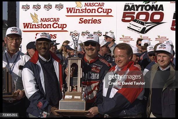 Dale Jarrett stands behind his trophy with Winston Cup officials in the winners circle after winning the Daytona 500 at Daytona Beach, Florida.