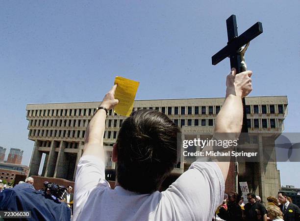 An opponent of same-sex marriage holds up a crucifix and a sheet of paper with the lyrics of "Battle Hymn of the Republic" during a rally at City...