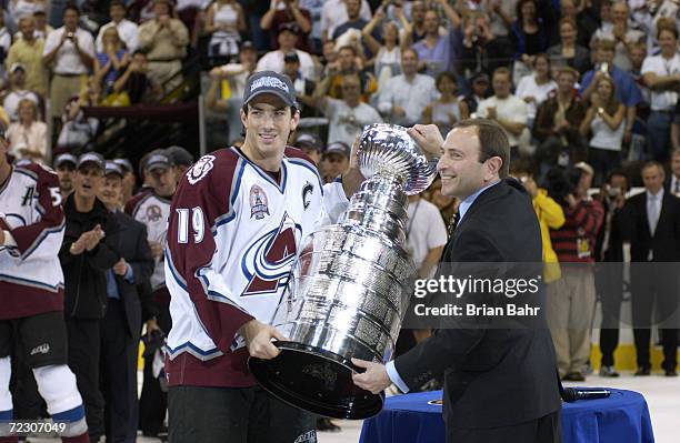Joe Sakic of the Colorado Avalanche and commissioner Gary Bettman hold the Stanley Cup after the Avalanche defeated the New Jersey Devils in game...