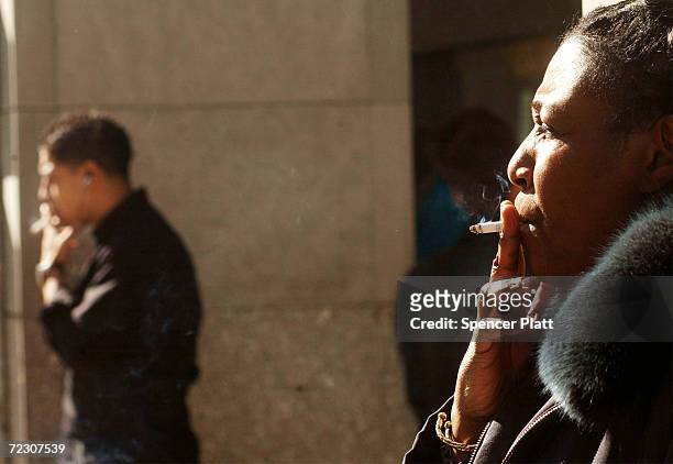 People smoke cigarettes outside of an office building February 19, 2002 in New York City. As part of his recent budget plan, New York Mayor Michael...