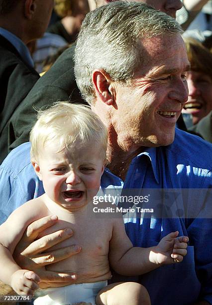 President George W. Bush holds a crying baby after speaking to supporters at a Victory 2004 rally October 9, 2004 in Chanhassen, Minnesota. Bush met...