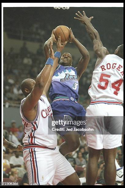 Forward Bryon Russell of the Utah Jazz goes up for two between Los Angeles Clippers forward Rodney Rogers and Kevin Duckworthy during a game at the...