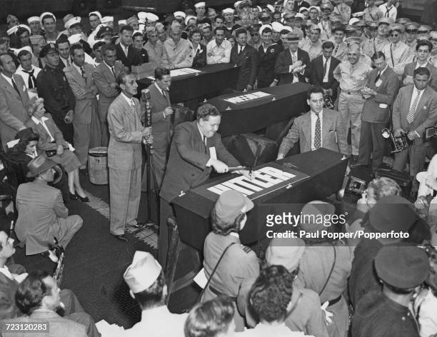 English actor Charles Laughton hammers a nail in to a coffin containing an effigy of Adolf Hitler during the launch of a World War II bond...
