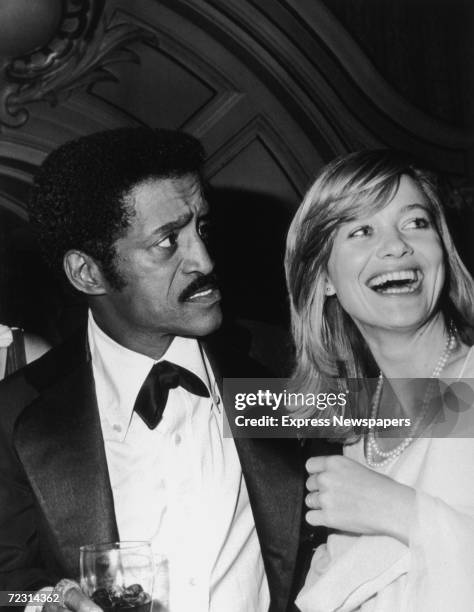 American dancer, singer and actor Sammy Davis Jr stands next to British actress Judy Geeson at a party, October 1976. Davis is wearing a tuxedo with...