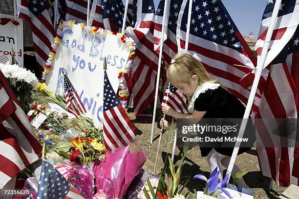 Five-year-old Jasmine Zahorecz plants a flag at an impromptu memorial forming at the entrance road to the Ronald Reagan Presidential Library and...