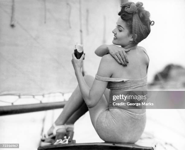 1950s: Woman applying suntan lotion.