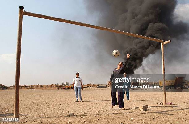 Iraqi orphan children play soccer at a local orphanage as smoke from burning oil rises in the background April 23, 2003 in Baghdad, Iraq. The...