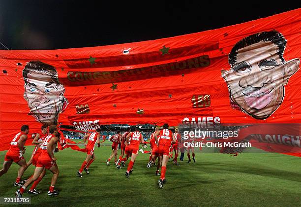 Sydney Swans players burst through the team banner during the round 4 AFL match between the Sydney Swans and the Kangaroos held at the Sydney Cricket...