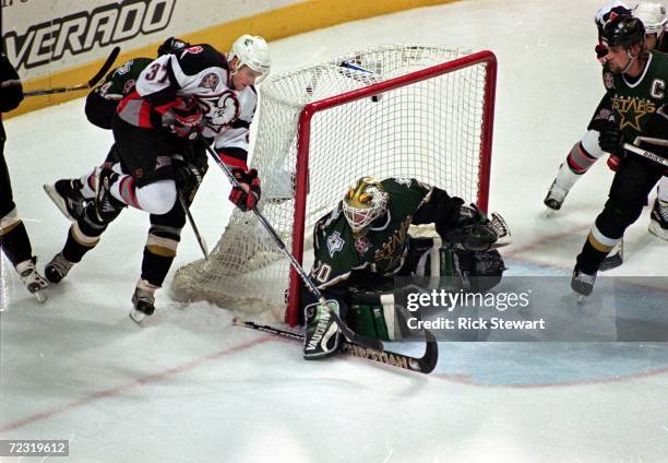 Curtis Brown of the Buffalo Sabres shoots the puck as Ed Belfour of the Dallas Stars blocks the goal at the Marine Midland Arena in Buffalo, New...