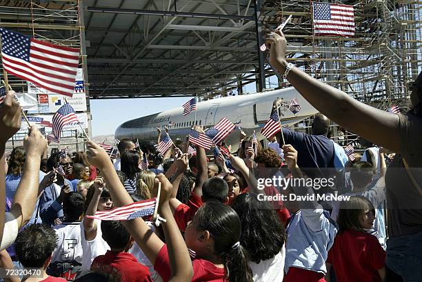 School children from Palmdale, California wave flags during the "moving-in ceremony" of the Ronald Reagan presidential-era Air Force One presidential...