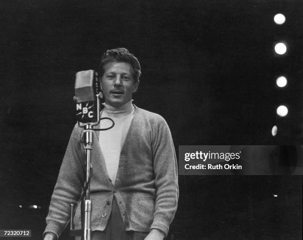 American comic film actor Danny Kaye , born David Daniel Kaminsky, wears a cardigan sweater over a turtleneck as he speaks into a WNBC radio...