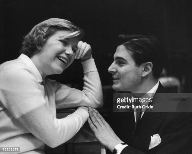 American film and television actress Barbara bel geddes sits and laughs as theater and television actor Donald Buka kneels down and touches her wrist...