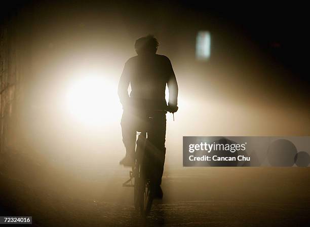 Man rides a bicycle on a road November 17, 2004 in Beijing, China. With people buying more cars, traffic jams in Beijing continue to be a major...