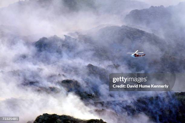 Fire department helicopter flies over smoke created by fires burning October 26, 2003 above Simi Valley, California. Hundreds of homes have been lost...