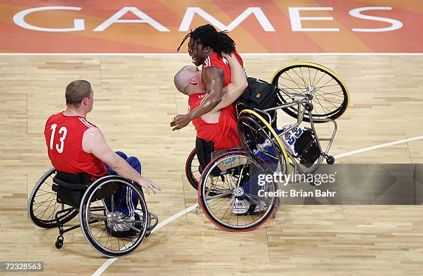 Ade Adepitan of Great Britain exults in the arms of teammate Jon Pollock as Peter Finbow moves to join them after defeating the USA in wheelchair...