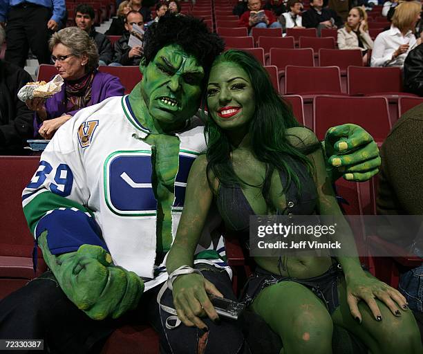 Two hockey fans dressed up in costumes sit in the stands before a game between the Vancouver Canucks and the Nashville Predators game on Halloween at...