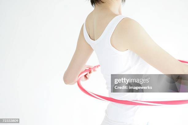 a young woman stands inside hula hoop as she gets ready for a hip exercise - hula hoop studio stock pictures, royalty-free photos & images