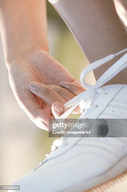 close up of white sports shoe is seen as one person ties the shoelace - lace fastener bildbanksfoton och bilder