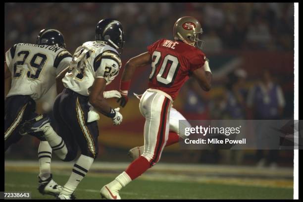 Wide receiver Jerry Rice of the San Francisco 49ers runs away from San Diego Chargers defensive backs Darren Carrington and Stanley Richard during...