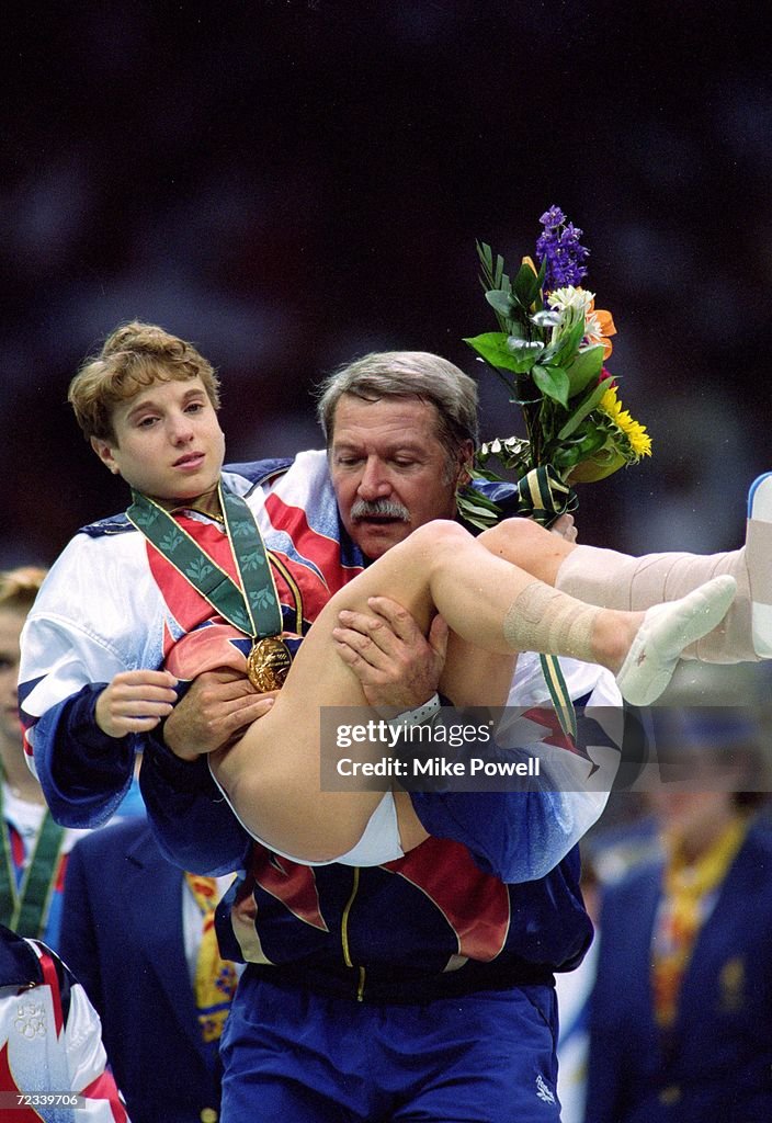 Kerri Strug of the USA is carried off the floor by her coach Bela Kerri Strug of the USA is carried off the floor by her coach Bela