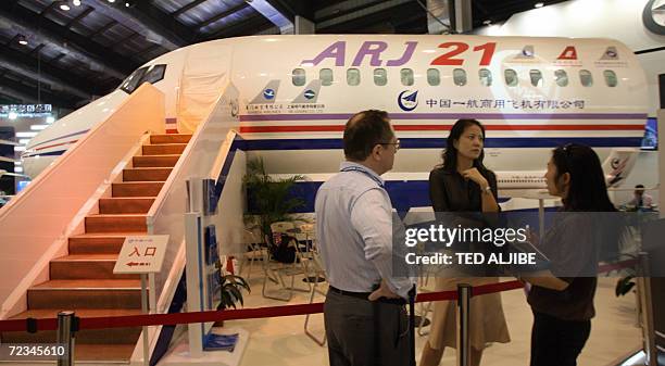 Visitors chat next to mock model of ARJ21 commercial passenger jet developed by China at the 6th China International Aviation and Aerospace...