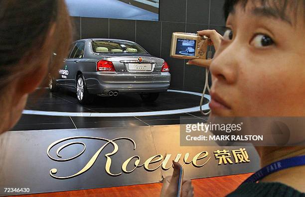 Chinese woman photographs a Chinese made Roewe car from the SAIC Motor Corp at the China International Industry Fair in Shanghai, 02 November 2006....