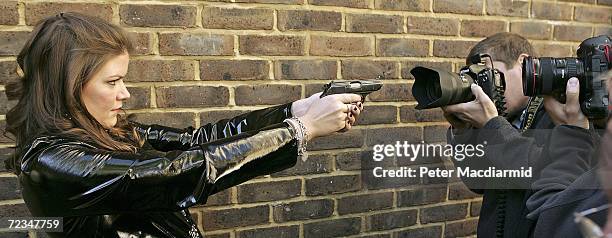 Leonie Ashfield from Christie's auctioneers points a Walther PPK handgun at photographers during promotion of a sale of prop guns from James Bond on...