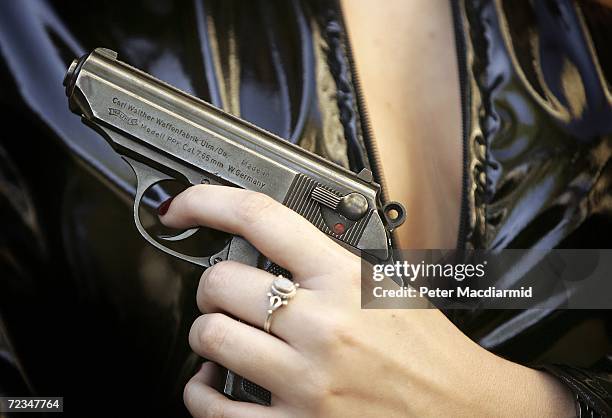 Leonie Ashfield from Christie's auctioneers poses with a prop Walther PPK handgun from 'From Russia With Love' during promotion of a sale of weapons...