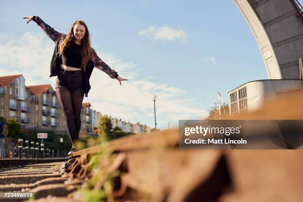 young woman balancing on train track, low angle view, bristol, uk - bristol stock-fotos und bilder