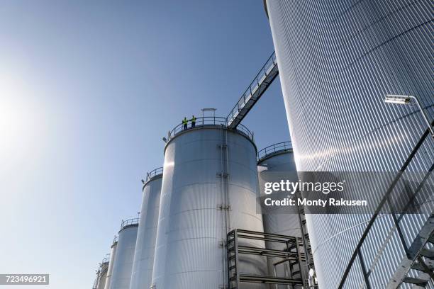 worker on top of storage tanks in oil blending factory - tank top stock-fotos und bilder