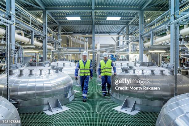workers with process machinery in oil blending factory - industria petrolifera foto e immagini stock