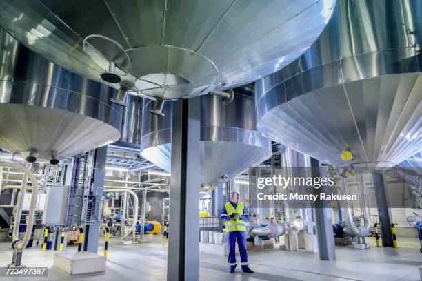 worker with process machinery in oil blending factory - ölraffinerie stock-fotos und bilder