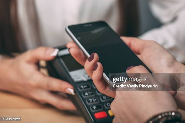 detail image of woman using smart phone to pay at counter - near field communication stock pictures, royalty-free photos & images