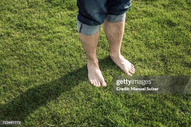 legs and bare feet of man standing on green grass - barefoot men - fotografias e filmes do acervo