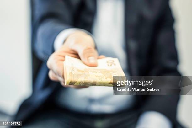 businessmans hand handing folded fifty euro notes - corruption imagens e fotografias de stock