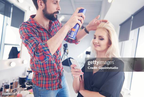 male hairdresser putting hairspray on model for photo shoot - backstage hairdresser stock pictures, royalty-free photos & images