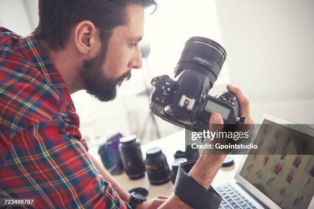 male photographer reviewing photo shoot on laptop in studio - macchina fotografica digitale foto e immagini stock