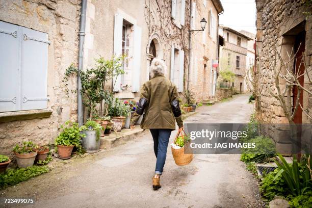 rear view of woman walking in narrow rural street, bruniquel, france - village france photos et images de collection