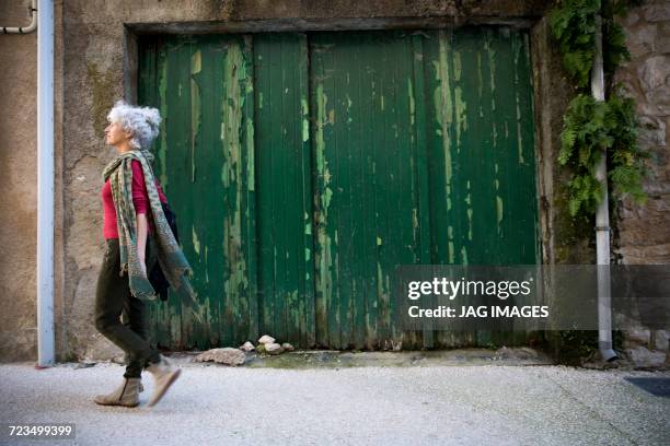 side view of woman walking in street. bruniquel, france - confident woman walking side view stock pictures, royalty-free photos & images