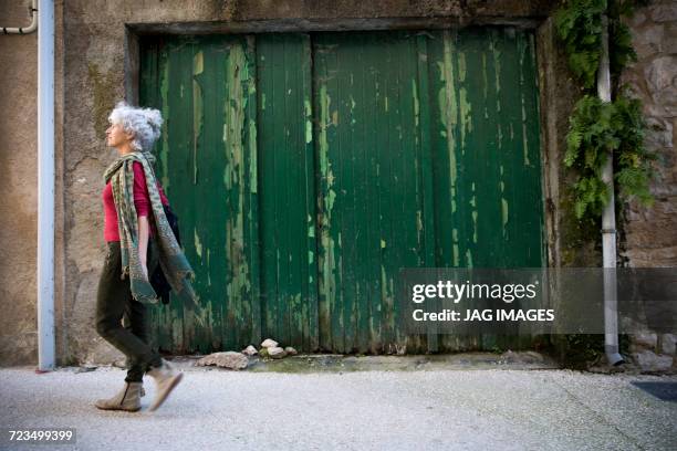 side view of woman walking in street. bruniquel, france - woman walking side view stock pictures, royalty-free photos & images